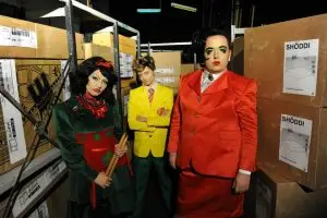 Group shot of Birdie Allslop, with Sue Hewlett as Chris Titmas a sleazy drag king in a yellow blazer with Scottee as floor manager Carole in a satin red ladies business suit
