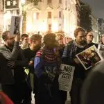 A photograph of members of audience holding placards from demonstrations. The main poster says No Going Back! There are about 10 people in the photo.