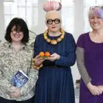 Photo portrait of Tracey holding her book Kitsch, Birdie holding two satsumas and Ruth not holding anything!