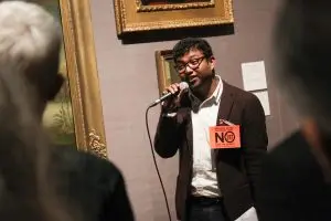 Rohit is speaking into a microphone in one of the galleries. He looks relaxed and confident. He is wearing a badge that says - End colonial anit queer laws - No 377! Defy the legacy of Babington Macaulay